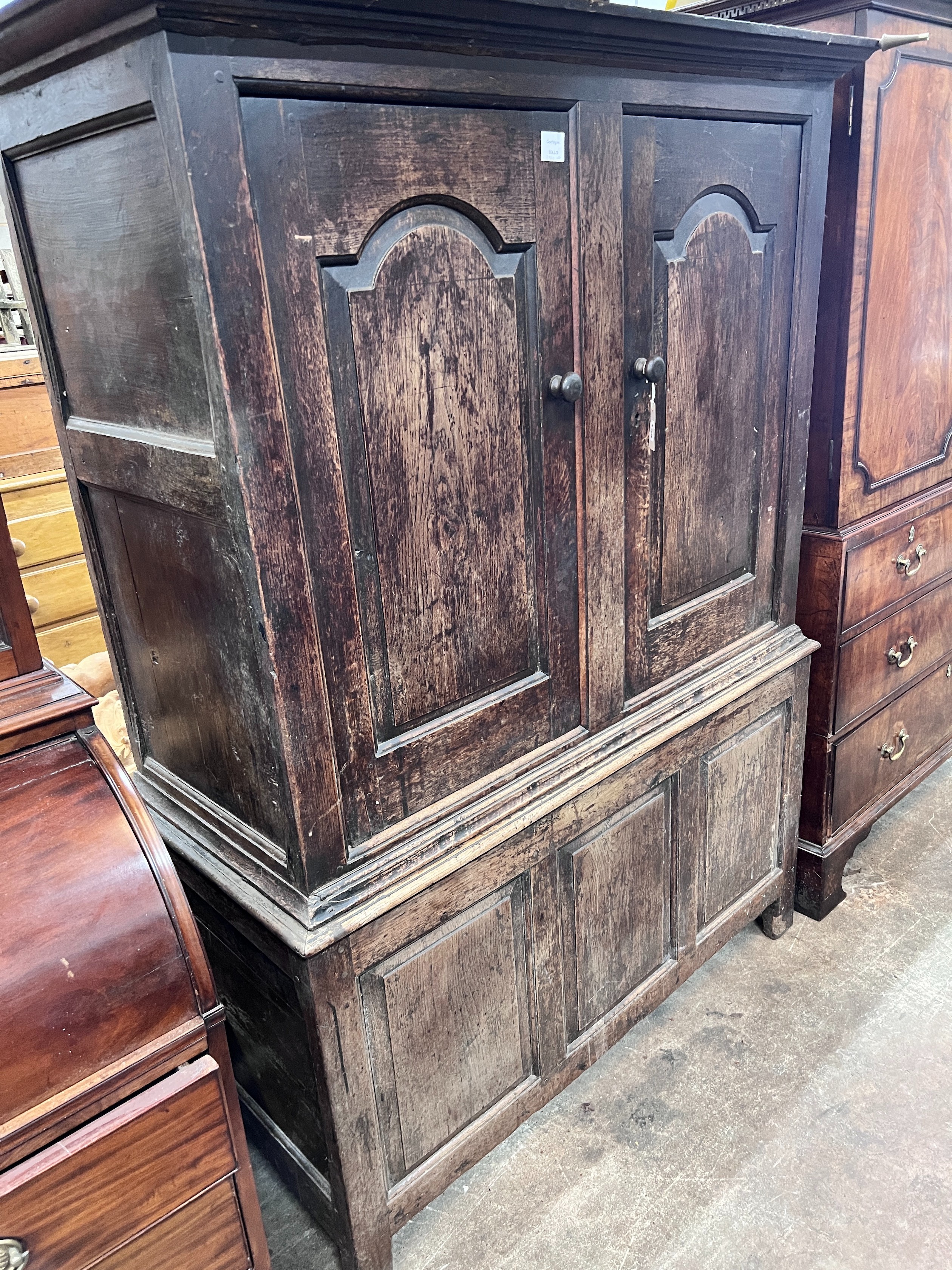 An early 18th century oak press cupboard two panelled doors and panelled base, width 127cm, depth 54cm, height 174cm *Please note the sale commences at 9am.
